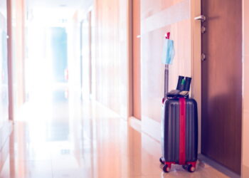 Medicine mask , wallet, Dollar bill, binoculars, alcohol spray and travel equipment on luggage in hotel. The concept of safe tourism equipment during the global Corona virus Covid-19 epidemic.