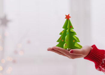 Woman hand holding a green christmas origami tree.