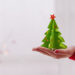 Woman hand holding a green christmas origami tree.