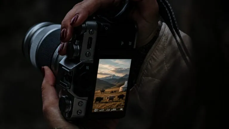 Fotógrafa revisa en su cámara una imagen de comunidades nómadas y pastizales, destacando la conservación de estos ecosistemas.